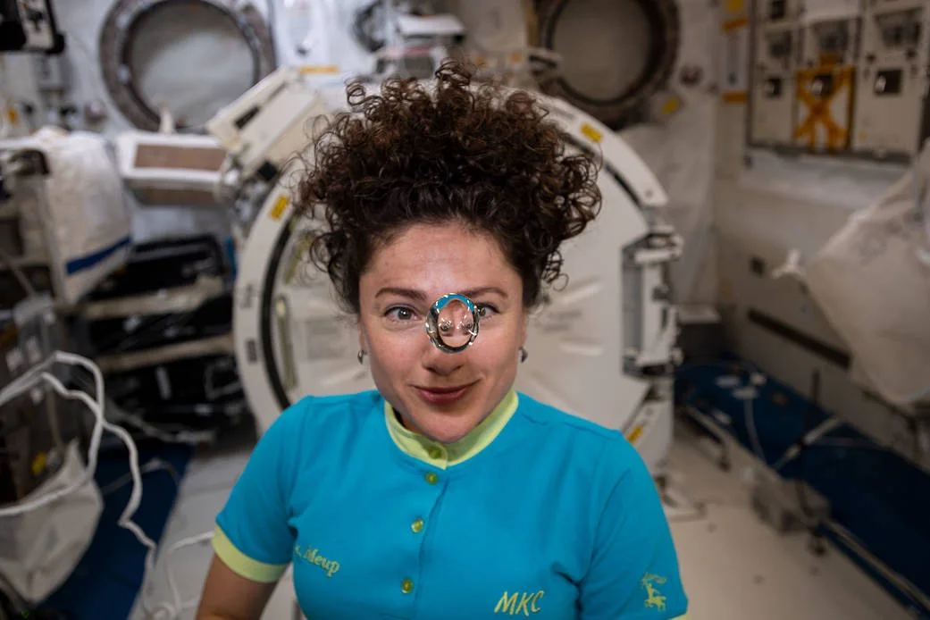 A floating sphere of water in front of astronaut Jessica Meir aboard the space station